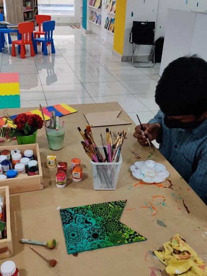 A young man works on a detailed mandala design on a banner, showing that our studio is a creative space for all ages and interests.