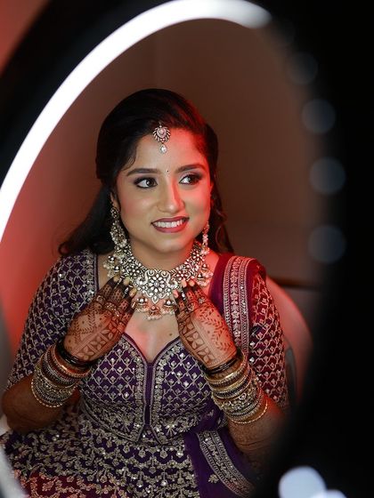 A beautiful bride framed by a ring light, her smile and her mehendi both shining bright for her reception.