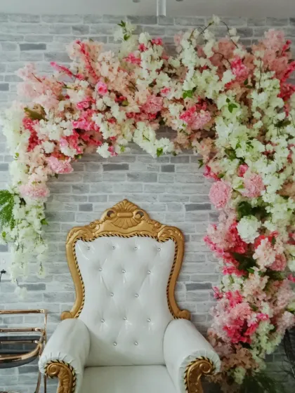 A stunning cherry blossom floral arch framing a white throne chair, creating a perfect photo spot for a baby shower or bridal shower.