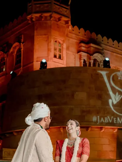 The groom's happy expression as he is framed by a projection of the couple's wedding hashtag. A modern and personal touch for a grand varmala ceremony at Suryagarh.