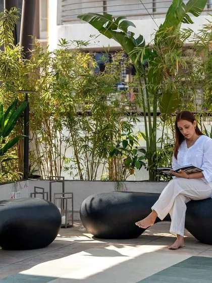 A quiet moment on the terrace, perfect for reading or enjoying a cup of tea. The custom pebble-like seating and abundant greenery create a sense of being in a private garden, high above the city.