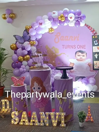 A beautiful fairy tale theme with a purple and gold color scheme. The setup includes a milestone board showing the baby's first year, which is a lovely personal touch.