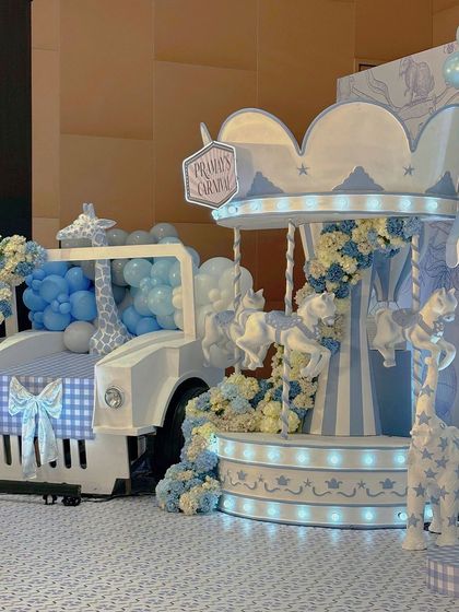 A whimsical carnival-themed first birthday, featuring a custom-built carousel and a truck bed filled with blue and white balloons. The soft color palette gives the classic carnival theme an elegant twist.