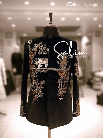 A black velvet Jodhpuri jacket on a mannequin, featuring intricate gold embroidery of florals and a majestic elephant motif. This piece blends royal symbolism with classic tailoring.