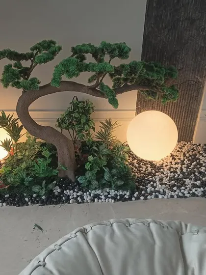 A full view of the lit bonsai arrangement, showing its placement next to a pillar and seating.