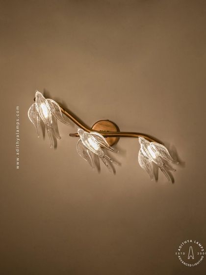 A close-up of our bird-themed wall sconce. Three delicate glass birds are mounted on a small rose-gold branch, providing a soft, ambient light. It's a charming accent piece that complements the larger chandeliers in the series or stands beautifully on its own.