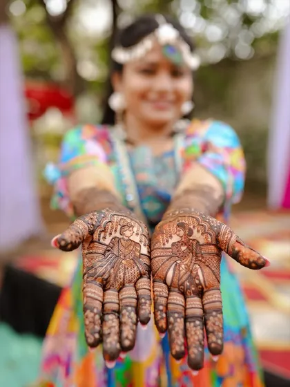A professional shot capturing the bride-and-groom portraits on the palms, with the happy bride in the background.