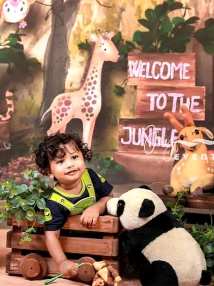 Welcome to the jungle. This adventurous kids' photoshoot features a jungle-themed backdrop, complete with friendly animal toys like a giraffe and panda, creating a fun and imaginative setting for your child.