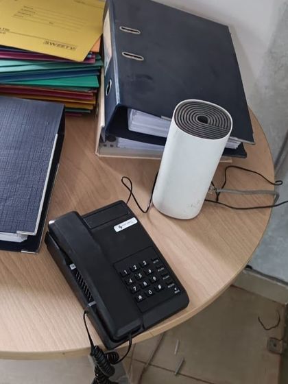 An intercom phone placed on a side table in an office, next to a Wi-Fi router, showing how our systems integrate into a modern office environment.