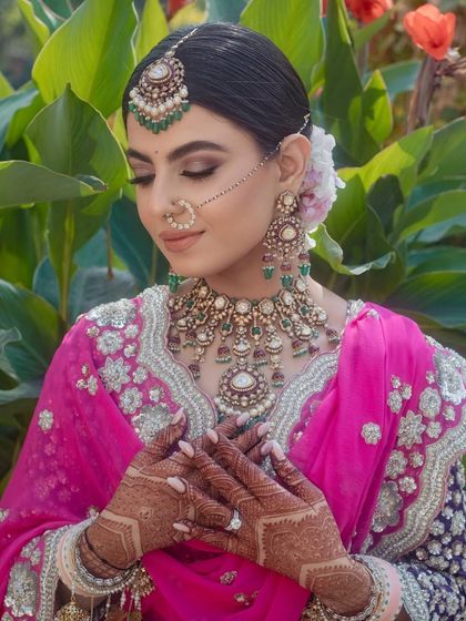 A close-up of the bride's hands and makeup, with the floral bun seen from the side.