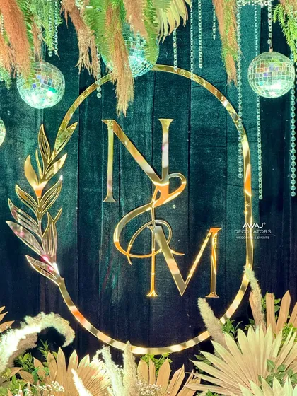 A close-up of the custom "NM" monogram, beautifully crafted in gold and set against a dark, textured backdrop.