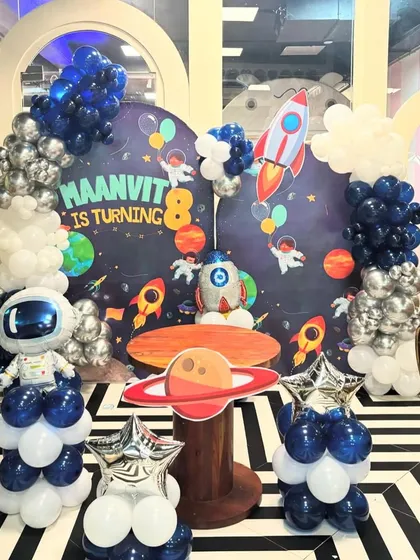 My space-themed parties are out of this world. This setup for an 8th birthday includes a detailed backdrop of the galaxy, balloon sculptures of an astronaut and rocket, and a custom cake table shaped like the planet Saturn.