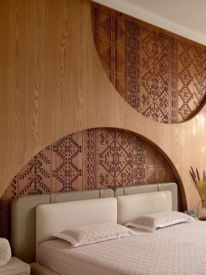 An intricately etched veneer-clad panel serves as the headboard in this bedroom. The detailed patterns add a layer of refined elegance and craftsmanship, making the wall itself a work of art.
