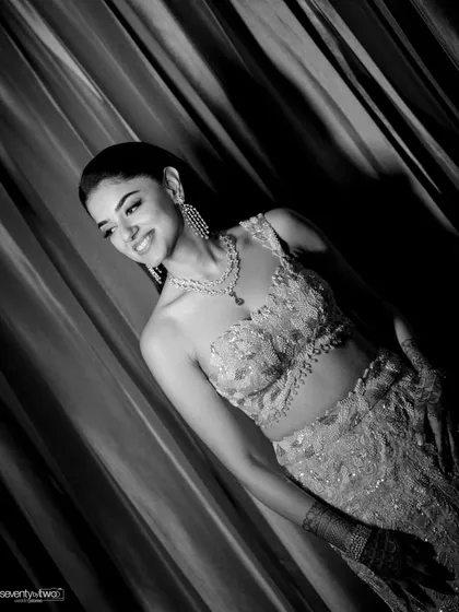 A candid shot of the bride, Divya, smiling during her sangeet night, her joy beautifully captured in this black and white photograph.