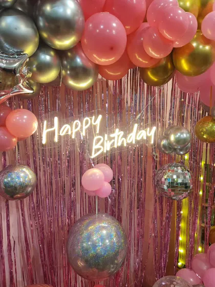 A close-up of the popstar party decor, showing the shiny pink backdrop, neon sign, and disco ball accents that create a fun, glamorous atmosphere.