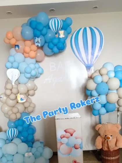A beautiful hot air balloon themed decoration in pastel shades of blue, peach, and beige, creating a dreamy atmosphere to welcome a new baby.