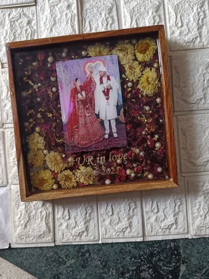 A lovely 10-inch square wooden frame preserving a mix of red and yellow wedding flowers. The couple's photo and a custom hashtag make this a truly personal piece of decor.