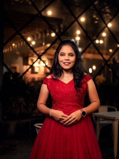 A beautiful portrait of the bride-to-be on her engagement night. Her red off-shoulder gown sparkles under the romantic cafe lights.