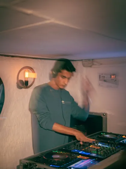 A motion-blurred photo showing the action of DJing, with my hands flying across the mixer at Olive.