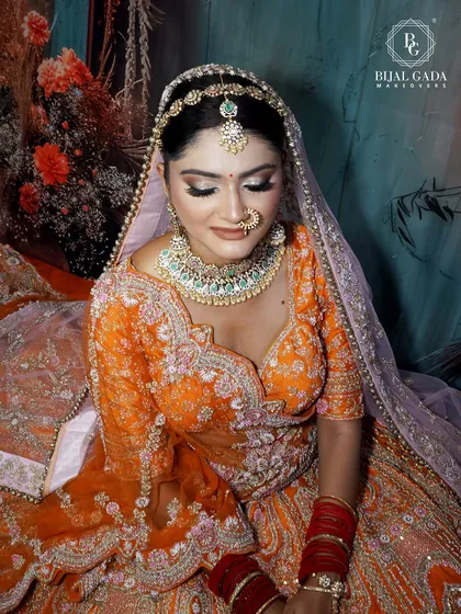A close-up shot with eyes gently closed, showing off the flawless eye makeup. The blend of warm tones on her eyelids complements the orange outfit perfectly.