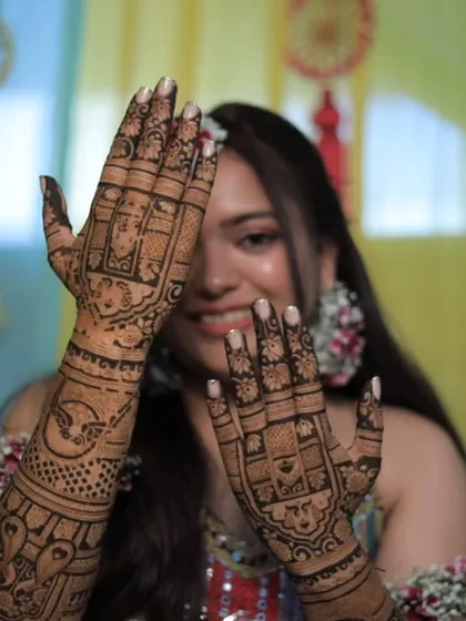 A happy bride peeks through her beautifully decorated hands, showing off the detailed grid and floral work we did for her.