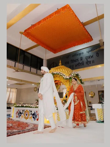 The bride and groom performing the Laavan Pheras during a traditional Sikh Anand Karaj ceremony in a Gurudwara.