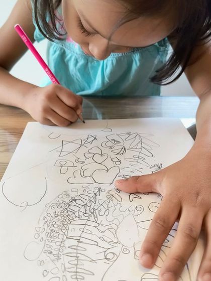 A close-up of a young artist working on her complex and creative zentangle design.