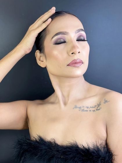 A serene pose with eyes closed, highlighting the beautiful purple and black blend of the smokey eye makeup.