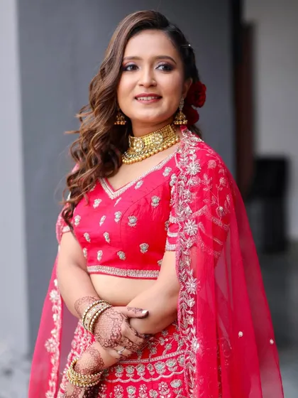 A full-length view of her festive red lehenga. The makeup is bold and beautiful, a perfect complement to her vibrant outfit.