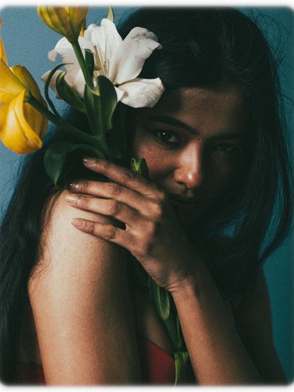 The model peeks through the flowers, using them as a veil. This creates a playful yet mysterious image, with the focus on her direct and captivating gaze.