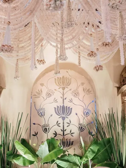 Intricate details of a heritage-inspired wedding stage, featuring golden jharokhas and a ceiling adorned with strings of white flowers. The design evokes a sense of royal history and timeless elegance.