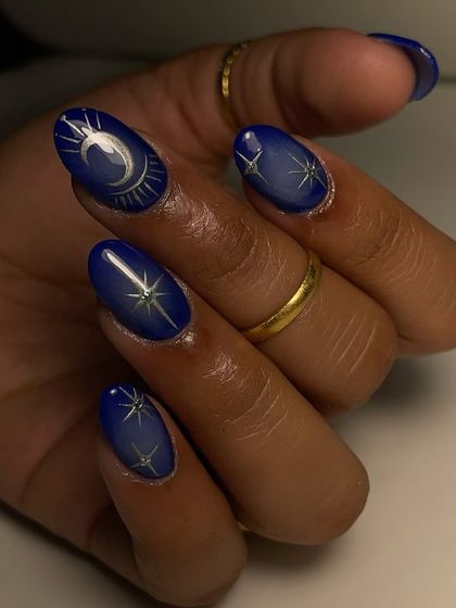 A stunning example of celestial nail art on acrylic extensions. This design uses a vibrant blue base with aura chrome and hand-painted stars and moons for a magical, cosmic look.