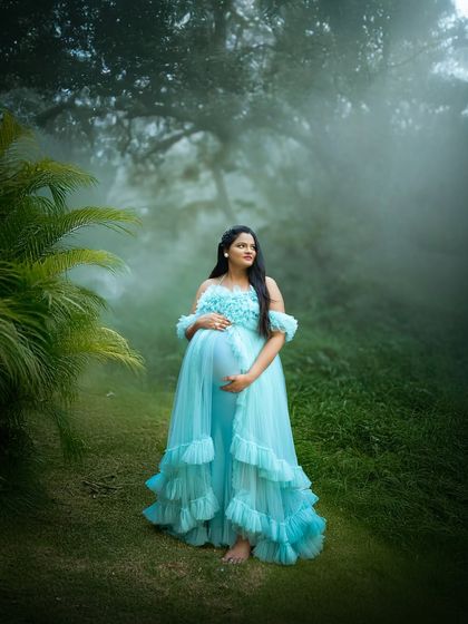 Surrounded by mist and lush greenery, this mom to be looks like a forest queen. The vibrant blue gown contrasts beautifully with the natural setting, creating a stunning visual.