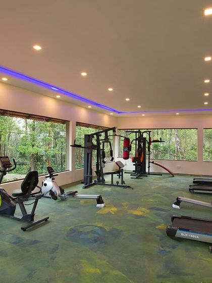 The well-equipped gym at Coorg Cliffs Resort, featuring large windows that look out into the forest, so you can stay active while still feeling connected to nature.