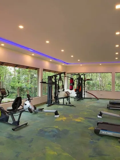 The well-equipped gym at Coorg Cliffs Resort, featuring large windows that look out into the forest, so you can stay active while still feeling connected to nature.