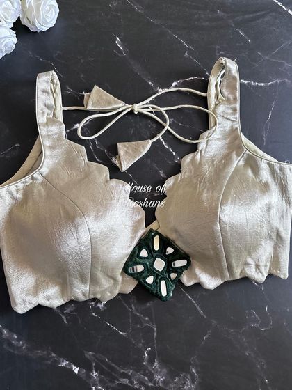 A simple yet elegant solid blouse with a scalloped neckline. This is a versatile piece that can be paired with almost any saree.