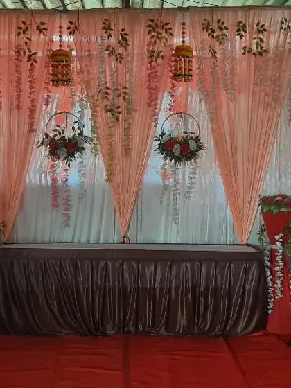 A stage setup for a formal event or conference, featuring a head table with a backdrop and floral arrangements.