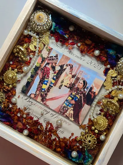This piece captures the grandeur of a traditional wedding. I preserved the couple's varmala, complete with intricate golden kaleera pieces and pearls, around their photo in a beautiful white wooden frame.