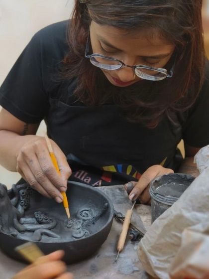 A student carefully sculpts an intricate underwater scene inside a bowl. This advanced project requires skill in creating miniature forms and composing a scene within a confined space.