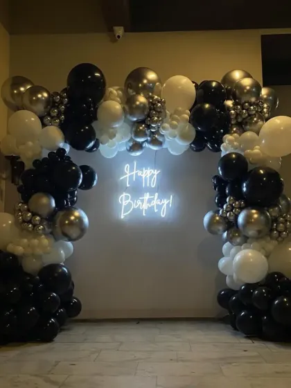 A classic black, white, and silver balloon arch with a neon sign, perfect for any modern celebration.