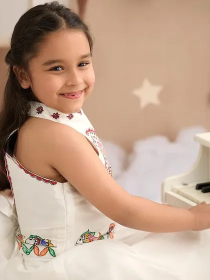 A bright and happy portrait of a young girl playing a toy piano. The dreamy, cloud-like floor and star decorations add to the whimsical, playful atmosphere of the session.