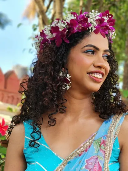 A Hawaiian princess look for a Haldi or Mehendi party, featuring a beautiful floral crown that complements the bride's natural curls and vibrant outfit.