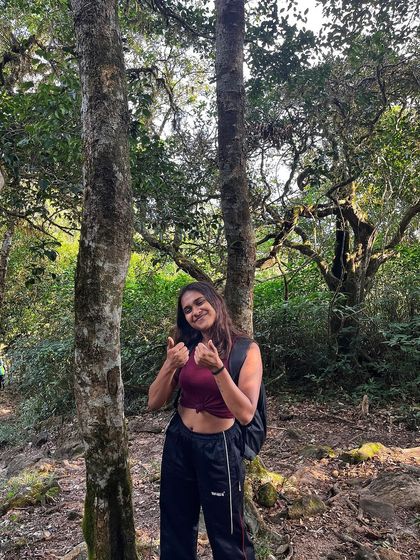 A happy trekker enjoying the beautiful forest section of the Kumara Parvatha trail. The journey is filled with lush greenery and serene spots.