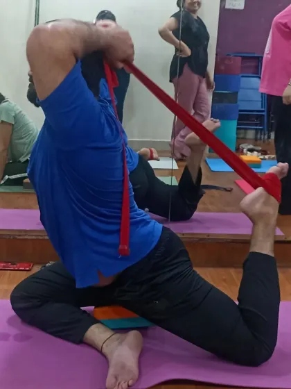 Mastering Rajakapotasana (King Pigeon Pose) requires flexibility and control. Here, a student uses a resistance band to assist in the pose, gradually improving their backbend.
