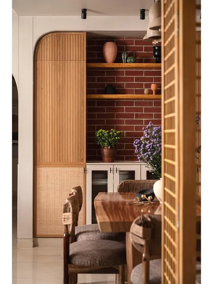 Another view of the dining area, framed by a wooden screen partition. This angle shows how the live-edge table and custom chairs create a warm and inviting space for family meals.