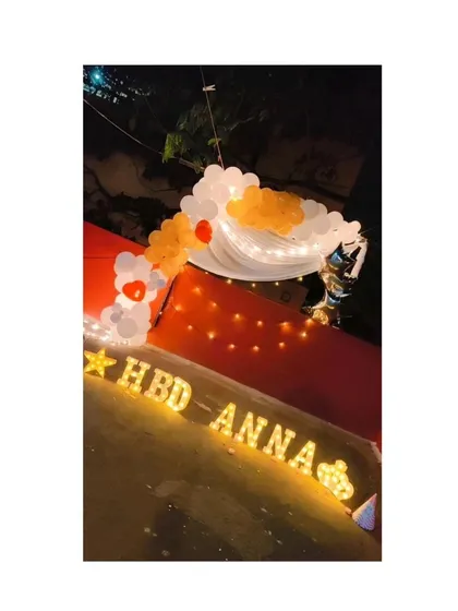 A midnight birthday surprise for a loved one. We set up this outdoor decor with 'HBD ANNA' marquee letters, a small balloon arch, and fairy lights to create a special moment as the clock struck twelve.
