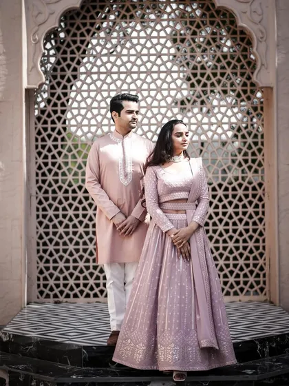 A formal pre-wedding portrait in front of an ornate archway. The couple's coordinated pastel outfits look elegant against the traditional architecture.