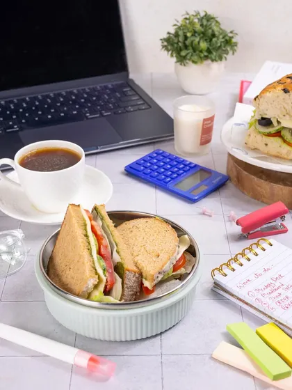 A classic work-from-home or office lunch scene. Styling a sandwich with a laptop, coffee, and stationery makes it relatable and perfect for brands targeting busy professionals.