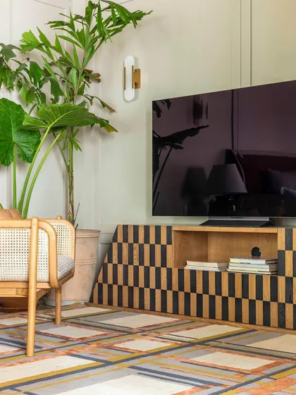 A detail from the 'Summer Haus' den, showcasing the intricate black-and-white pattern of the custom media unit. This piece is set against a colorful, geometric rug, demonstrating our bold and playful approach to mixing patterns.