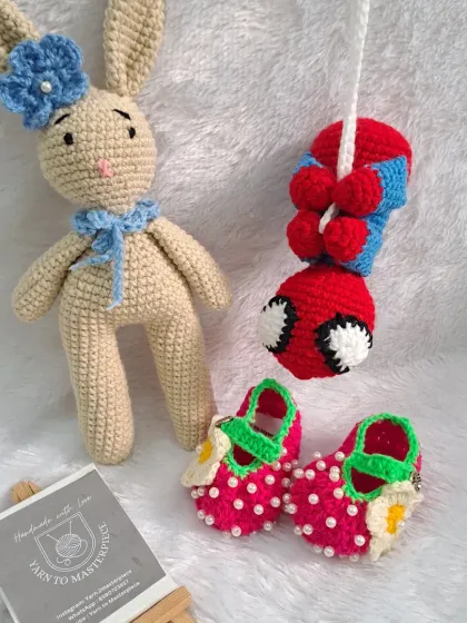 A custom baby gift hamper with a bunny, a hanging Spider-Man toy, and strawberry-themed booties.